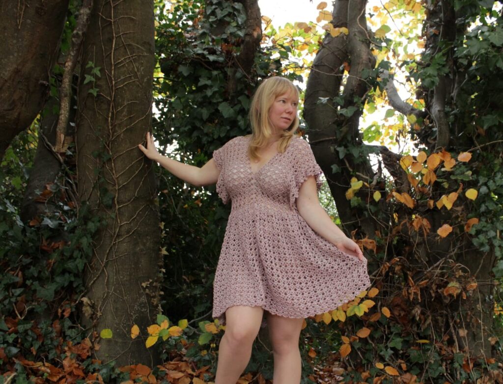 Full body of a pink flowy crochet dress.